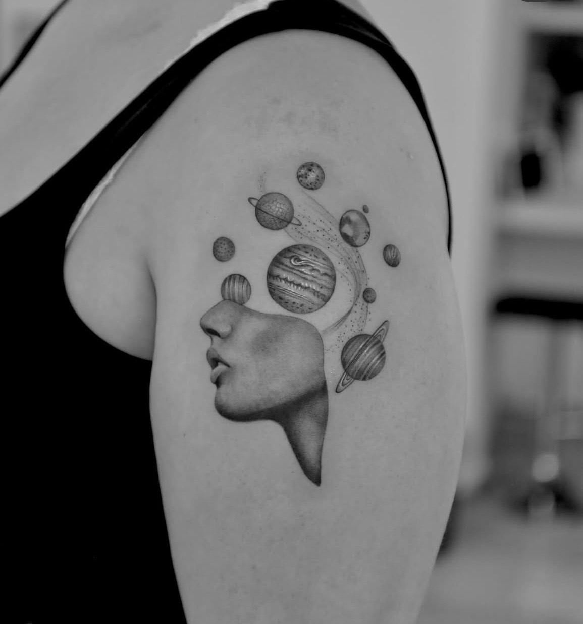 A face in profile with planets rising from the head.