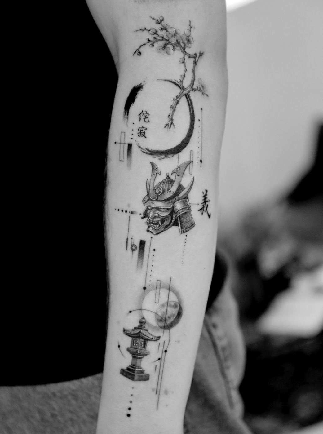 Arm piece: a cherry blossom branch over a brush-stroke circle with the characters 侘寂, a samurai helmet and mask, the character 義, a stone lantern and a moon, linked by fine lines and dots.